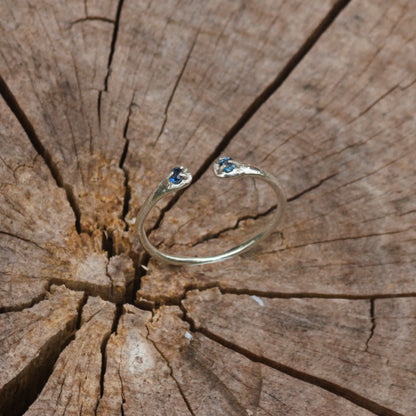 split band sterling silver ring with two bright blue sapphire gemstones on a wooden stump