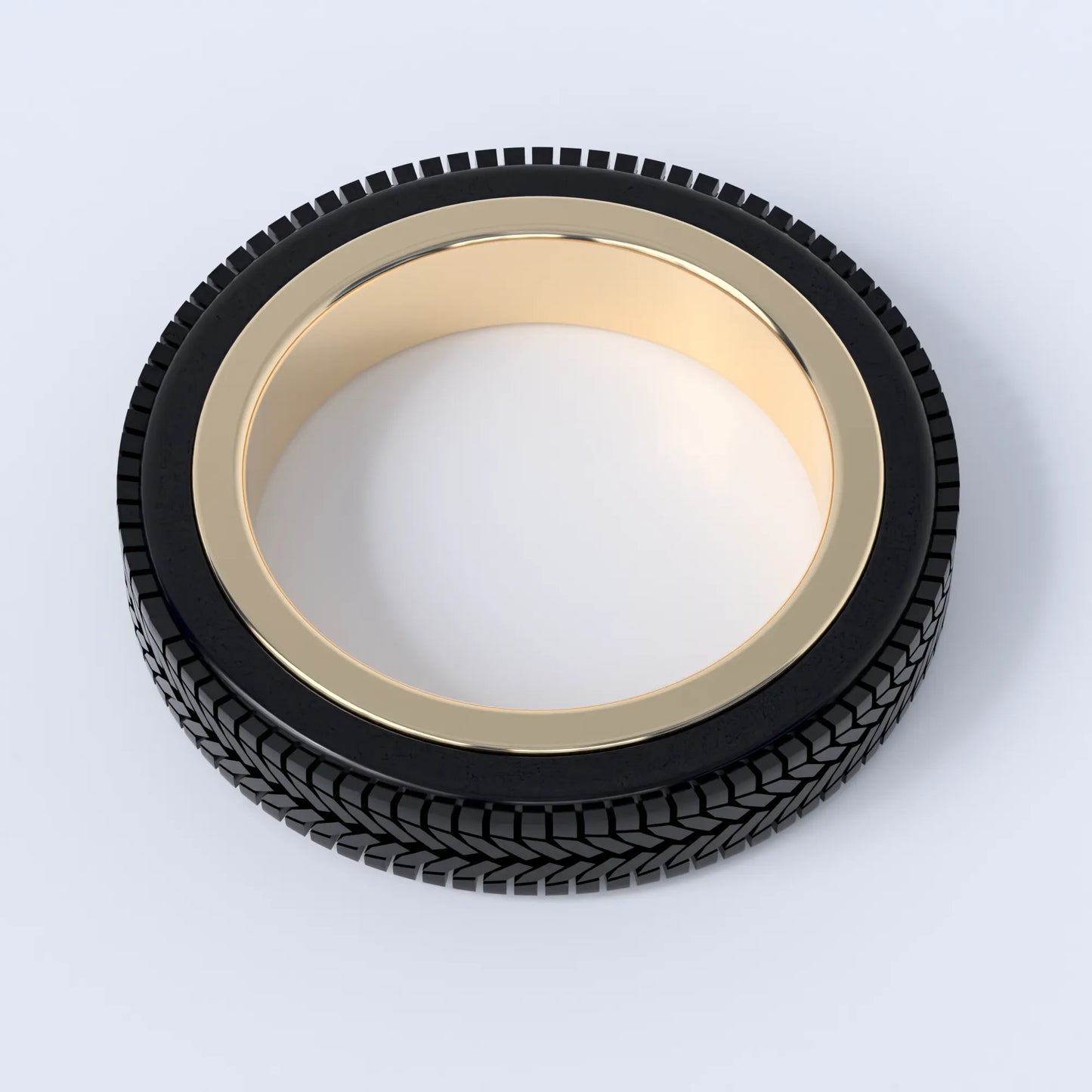 Gold ring on a white background, this ring is shaped like a car's tyre, and shows the design in 14ct gold with the 3d printed tyre